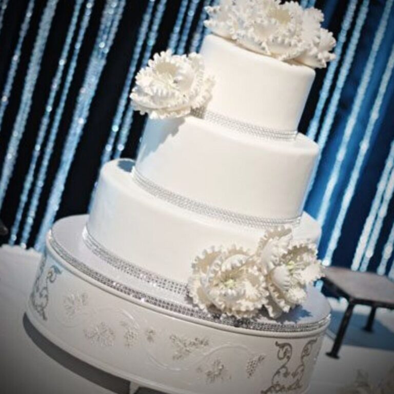 A wedding cake that is spotlit. Blue uplights are in the background