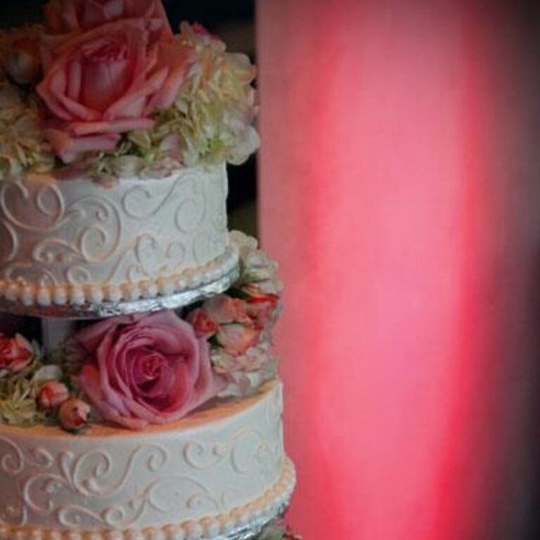 A wedding cake with pink uplights in the background