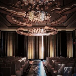 uplighting, a chandelier, and pattern on the aisle of a wedding setup in a ballroom