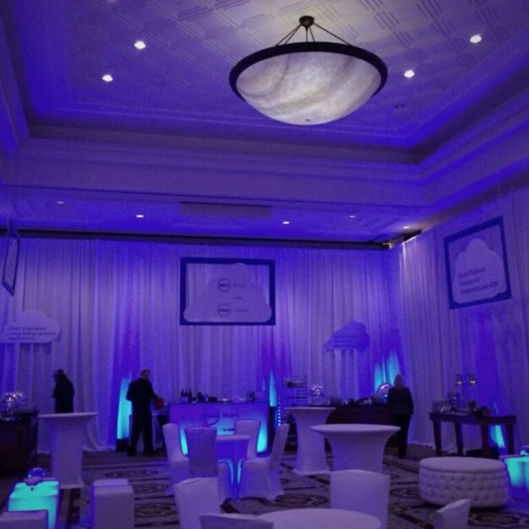 Blue uplights and white drape in a ballroom for a party.